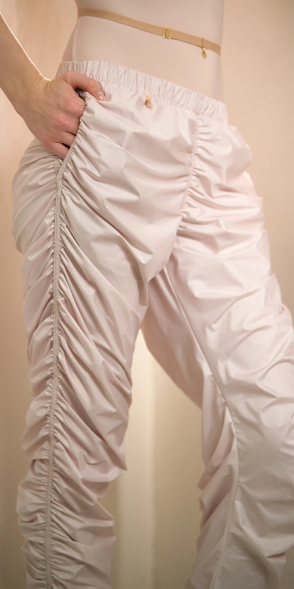Womens draped track pants in soft pink close up with hand in pocket
