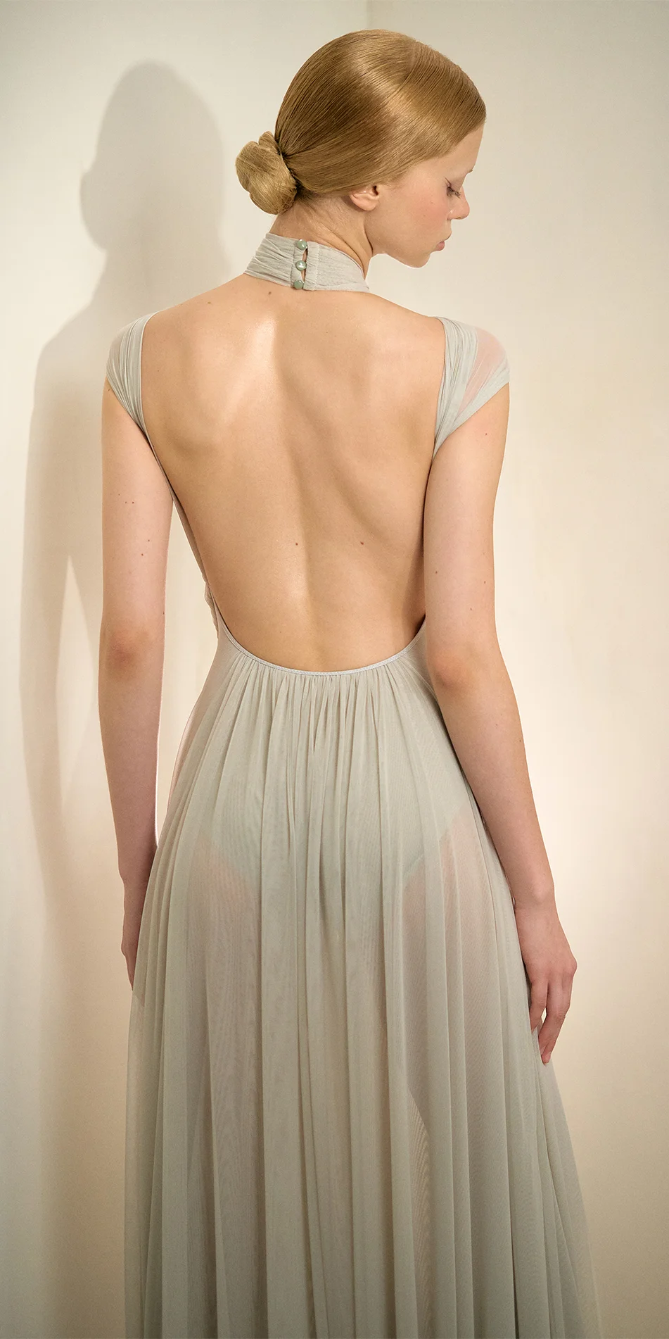 Knotted halter maxi dress in sage green back of medium shot model looking down