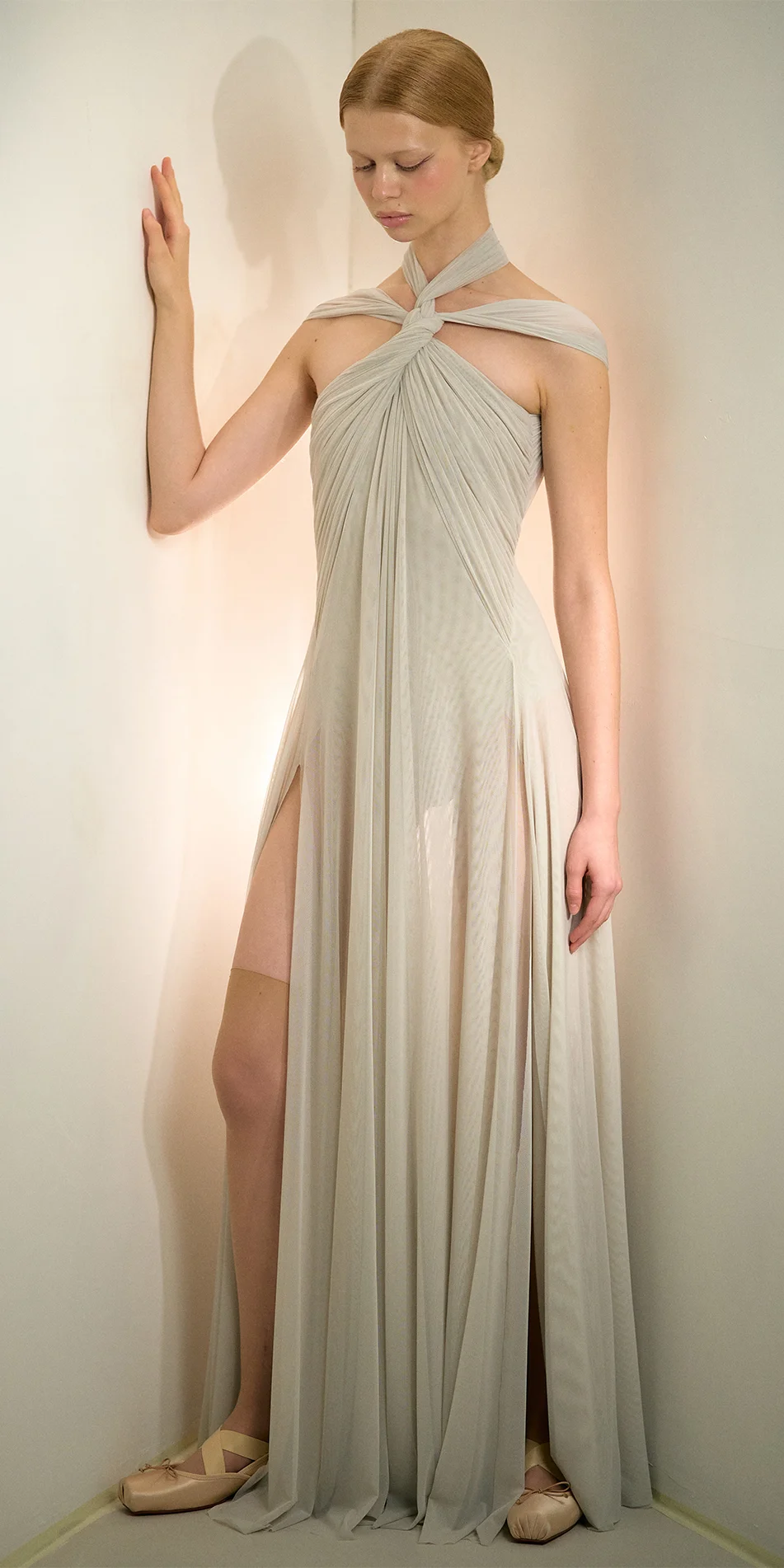 Knotted halter maxi dress in sage green full shot with a hand on the wall